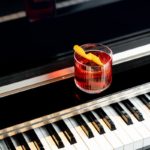 A glass of alcohol sitting on top of a piano